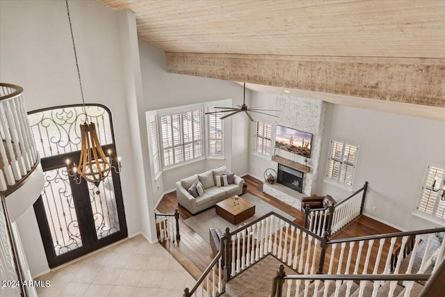 living room with french doors, light hardwood / wood-style flooring, a fireplace, wooden ceiling, and ceiling fan with notable chandelier