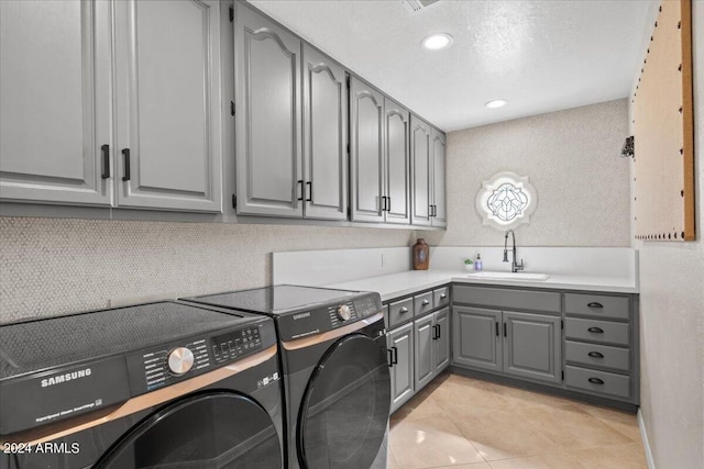 laundry room featuring light tile patterned floors, cabinets, sink, and washing machine and clothes dryer