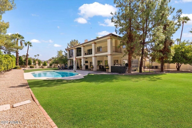 rear view of property with a balcony, a patio, a fenced in pool, and a lawn