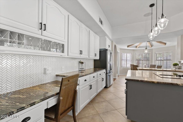 kitchen featuring dark stone countertops, white cabinets, decorative light fixtures, and tasteful backsplash