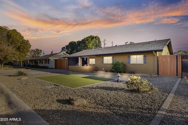 ranch-style home with a garage, fence, driveway, roof with shingles, and stucco siding