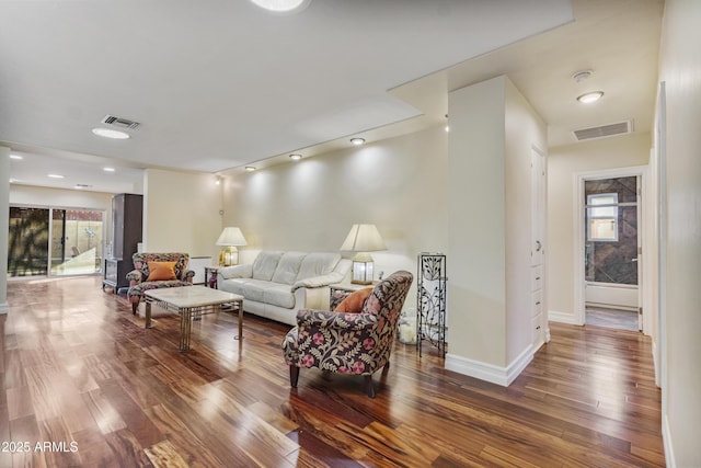 living room featuring wood finished floors, visible vents, and baseboards