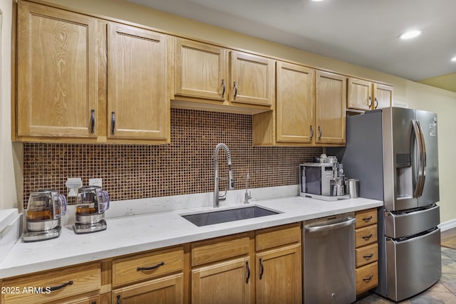 kitchen featuring appliances with stainless steel finishes, a sink, backsplash, and light stone counters