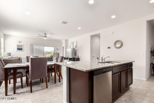 kitchen with stainless steel dishwasher, ceiling fan, sink, a center island with sink, and light tile patterned floors