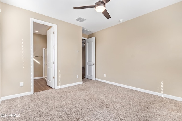 unfurnished bedroom with a walk in closet, ensuite bath, ceiling fan, and light colored carpet