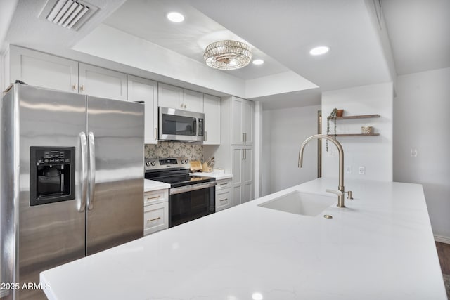 kitchen featuring visible vents, open shelves, a sink, stainless steel appliances, and tasteful backsplash