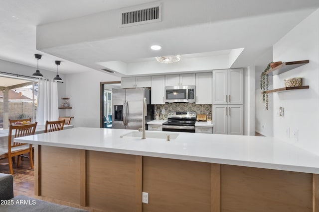 kitchen with visible vents, light countertops, decorative backsplash, appliances with stainless steel finishes, and wood finished floors