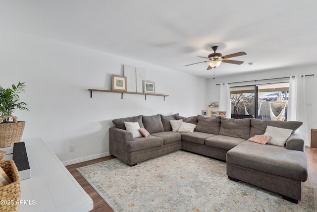 living room with ceiling fan, baseboards, and wood finished floors