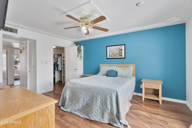 bedroom featuring visible vents, wood finished floors, baseboards, ceiling fan, and a spacious closet