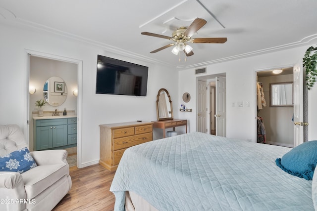 bedroom with visible vents, a ceiling fan, ensuite bathroom, a sink, and light wood finished floors