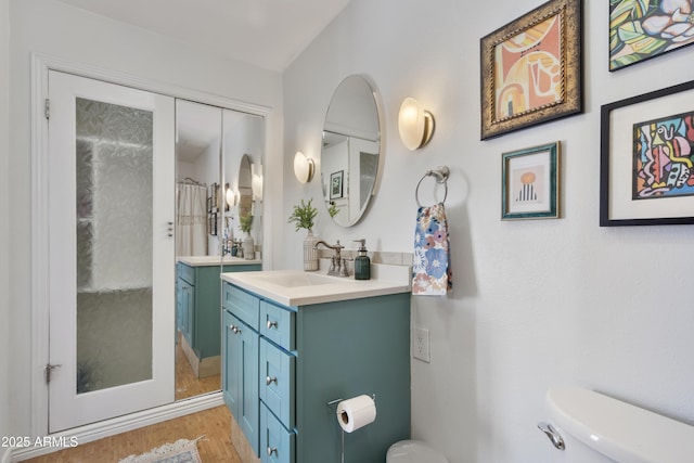 bathroom featuring vanity, curtained shower, toilet, and wood finished floors