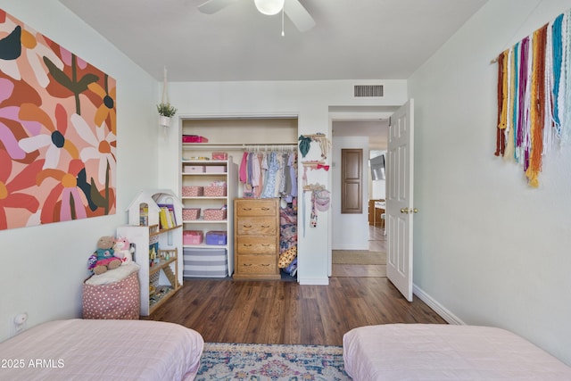 bedroom featuring wood finished floors, baseboards, visible vents, ceiling fan, and a closet