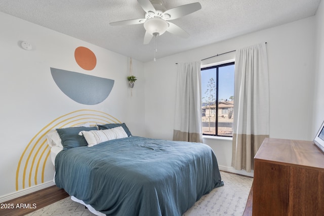 bedroom featuring light wood finished floors, ceiling fan, a textured ceiling, and baseboards