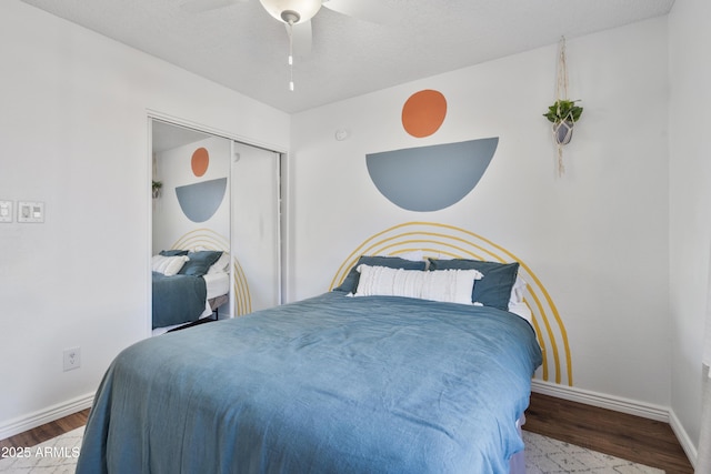 bedroom with a closet, baseboards, wood finished floors, and a ceiling fan