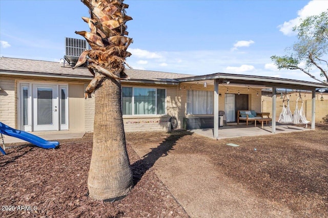 back of house with french doors, central air condition unit, brick siding, and a patio area