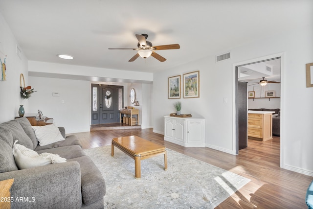 living area featuring visible vents, ceiling fan, baseboards, and wood finished floors