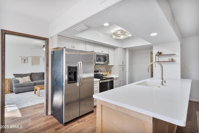 kitchen featuring a peninsula, a sink, stainless steel appliances, light countertops, and light wood-style floors