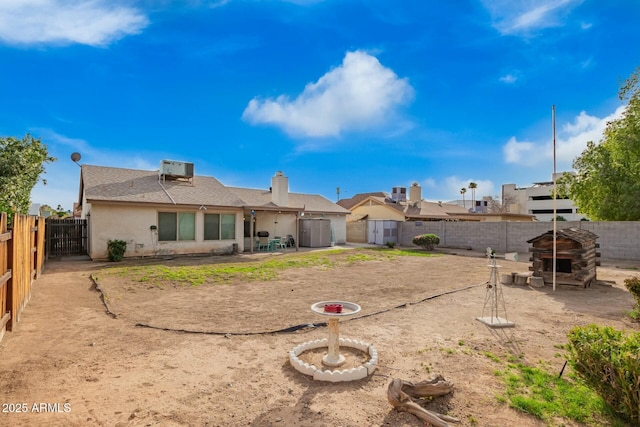back of property with an outbuilding, stucco siding, central AC unit, a patio area, and a fenced backyard