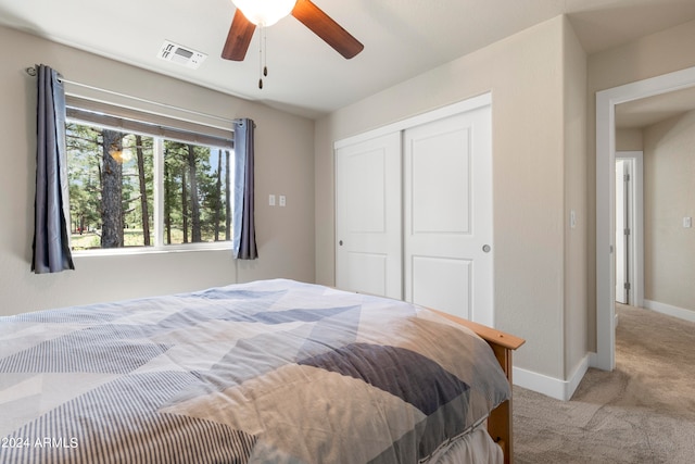 bedroom with a closet, ceiling fan, and light carpet