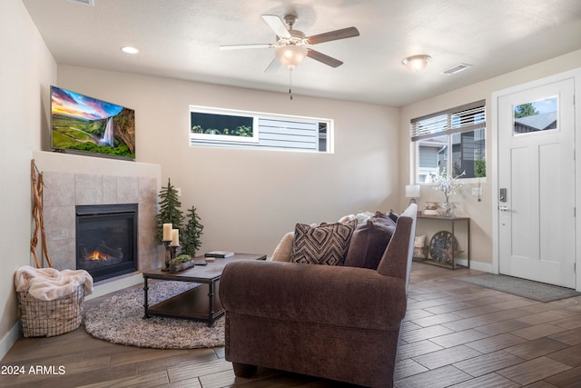 living room with hardwood / wood-style floors, ceiling fan, and a tile fireplace