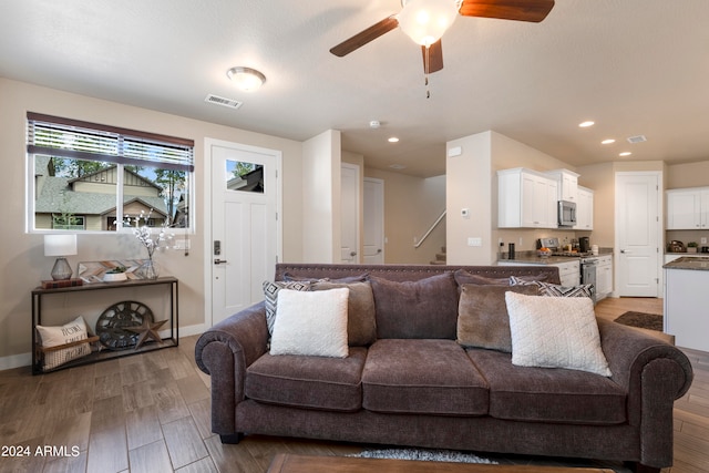 living room featuring wood-type flooring and ceiling fan