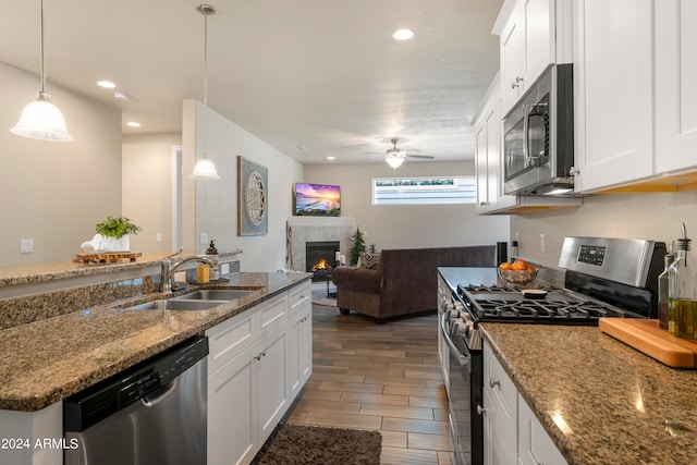 kitchen featuring white cabinets, appliances with stainless steel finishes, stone countertops, sink, and ceiling fan