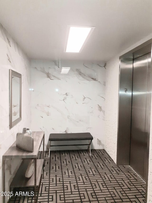 bathroom with elevator and tile walls