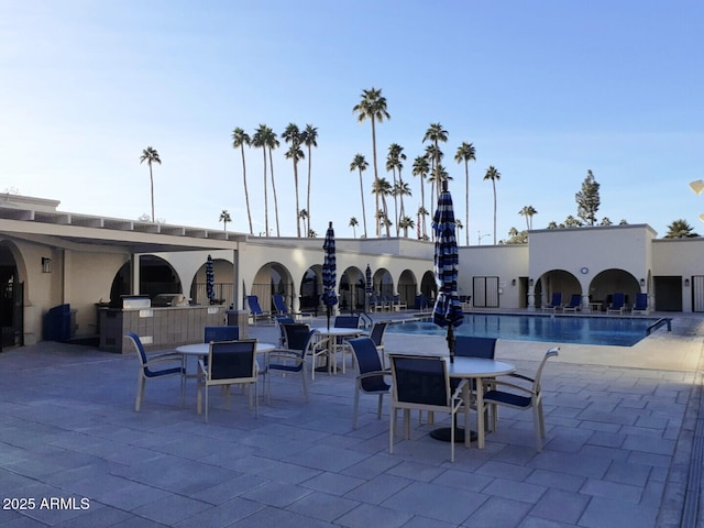 view of patio featuring an outdoor kitchen, outdoor dining space, and a community pool