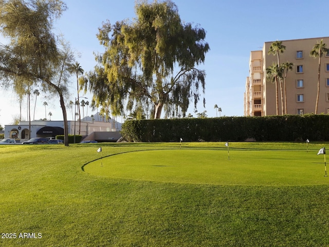 surrounding community featuring an area to practice putting and a lawn
