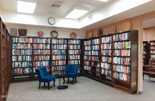sitting room featuring wall of books and carpet
