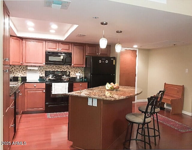 kitchen featuring black appliances, dark wood finished floors, recessed lighting, a kitchen island, and tasteful backsplash
