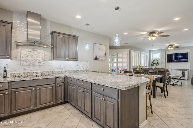 kitchen with light tile patterned floors, black electric stovetop, a peninsula, wall chimney range hood, and decorative backsplash