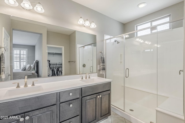 full bathroom with double vanity, tile patterned floors, a sink, and a shower stall