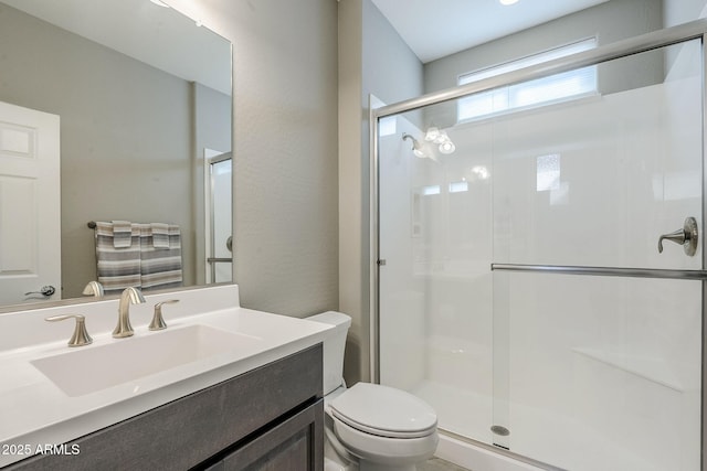 full bathroom featuring vanity, a shower stall, and toilet