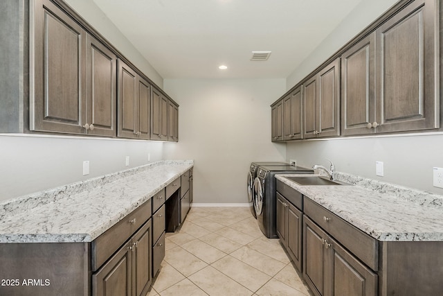 washroom with a sink, visible vents, baseboards, cabinet space, and washer and clothes dryer