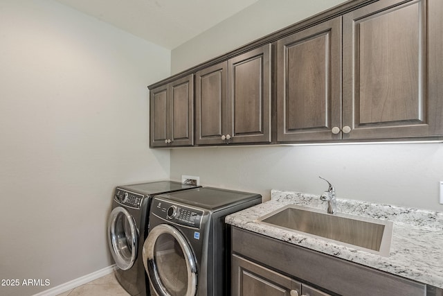 laundry area featuring cabinet space, light tile patterned flooring, a sink, independent washer and dryer, and baseboards