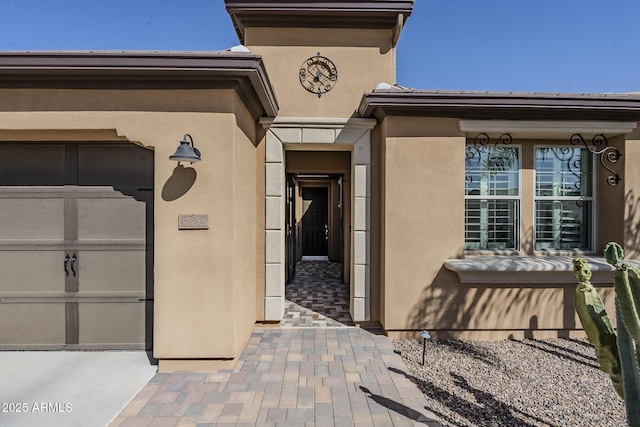 entrance to property featuring a garage and stucco siding