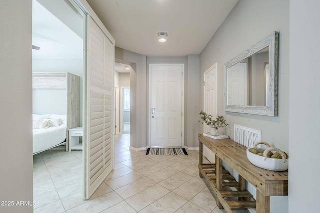 hall with light tile patterned floors, visible vents, and baseboards