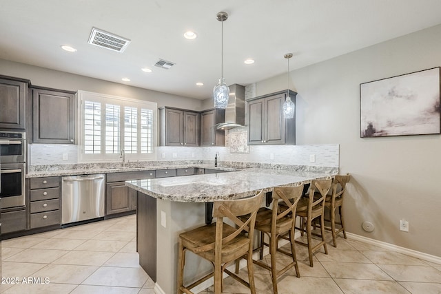 kitchen with appliances with stainless steel finishes, visible vents, wall chimney range hood, and light tile patterned floors