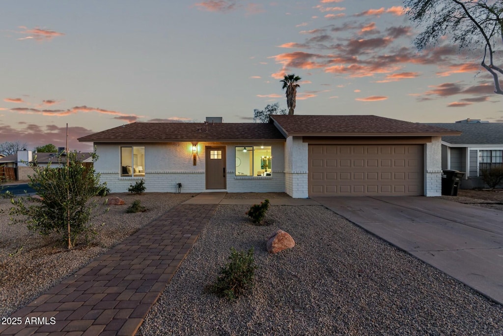 ranch-style house featuring brick siding, driveway, and an attached garage