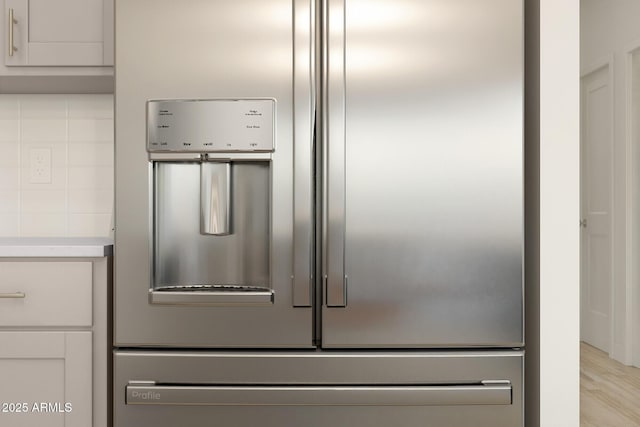 interior details featuring white cabinetry, stainless steel fridge, and light hardwood / wood-style flooring