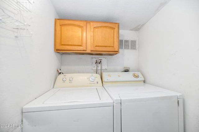 laundry room featuring cabinets, a textured ceiling, and washing machine and dryer