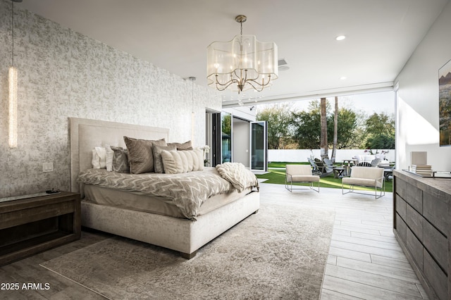 bedroom featuring a chandelier, hardwood / wood-style floors, and expansive windows