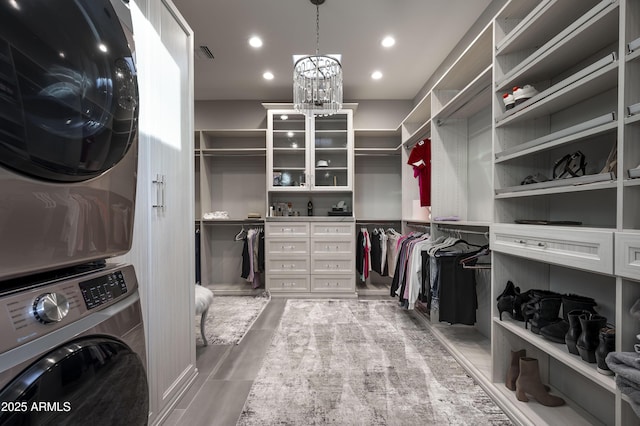 spacious closet with an inviting chandelier and stacked washer and clothes dryer