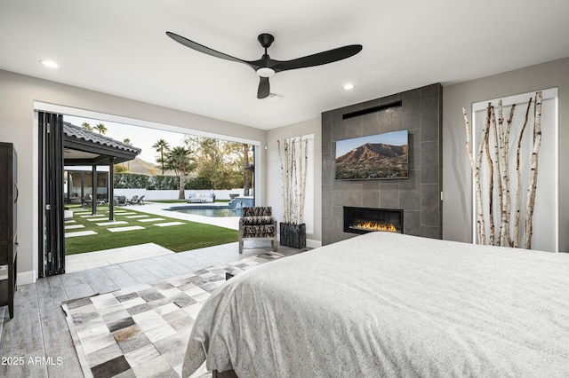 bedroom with ceiling fan, access to exterior, and a tile fireplace