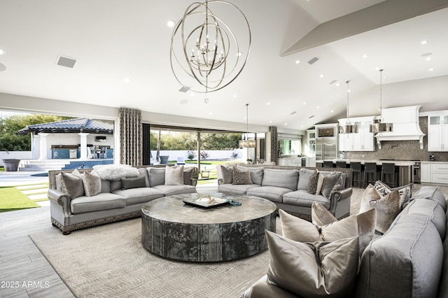 living room with a chandelier, a wealth of natural light, and vaulted ceiling