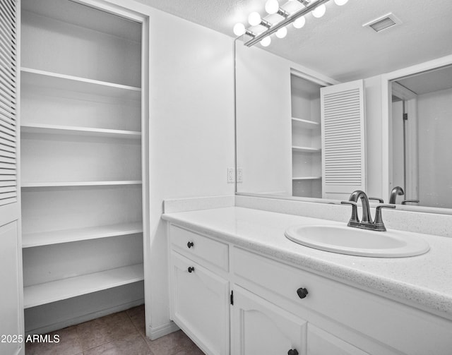 bathroom with a textured ceiling, visible vents, tile patterned flooring, and vanity