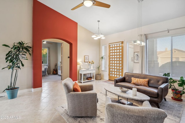 tiled living room with a ceiling fan, arched walkways, high vaulted ceiling, healthy amount of natural light, and baseboards