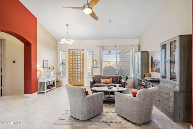 living room featuring high vaulted ceiling, light tile patterned flooring, ceiling fan, arched walkways, and baseboards