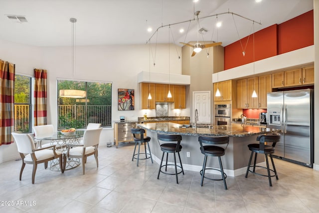 kitchen with stainless steel appliances, a high ceiling, a sink, a large island, and a breakfast bar